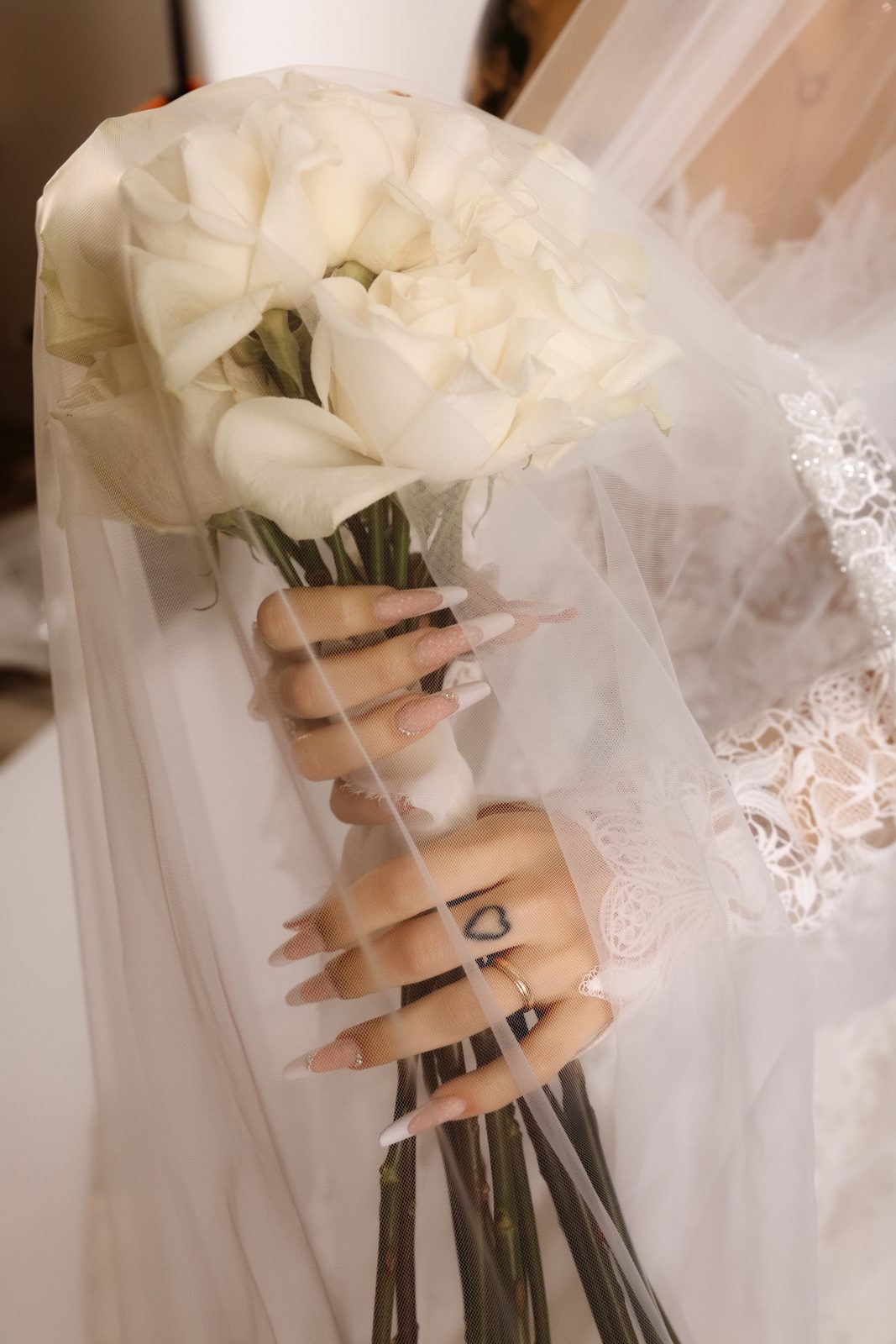 Mani della sposa con bouquet di rose bianche